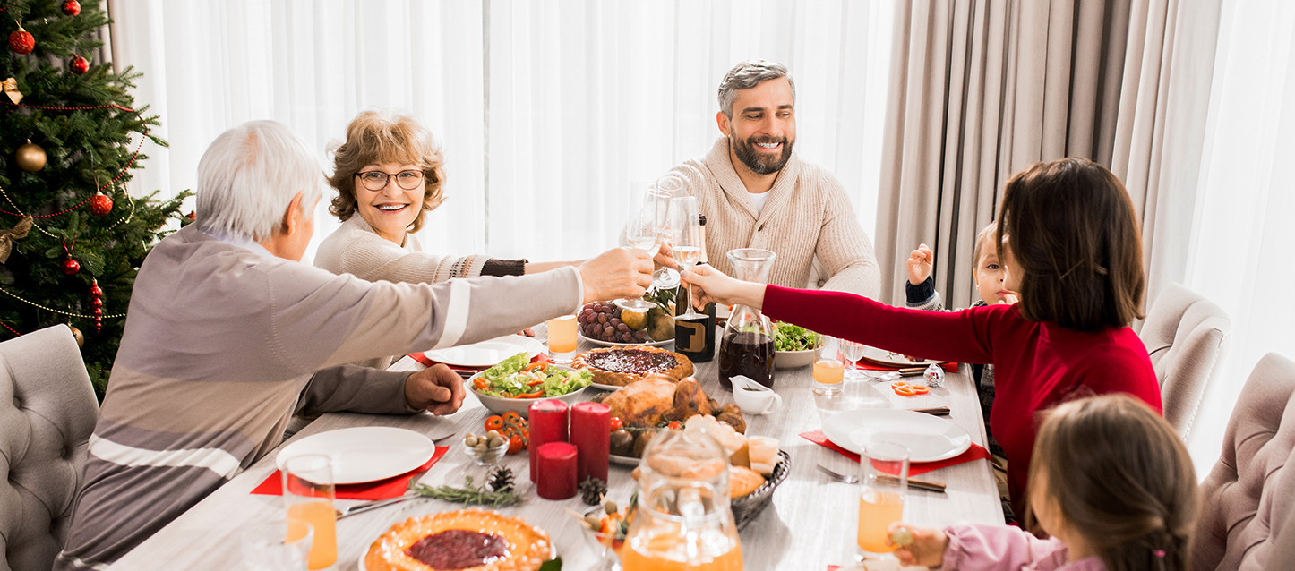 Repas familial avec deux grands-parents, deux parents et deux enfants durant lequel les adultes trinquent.