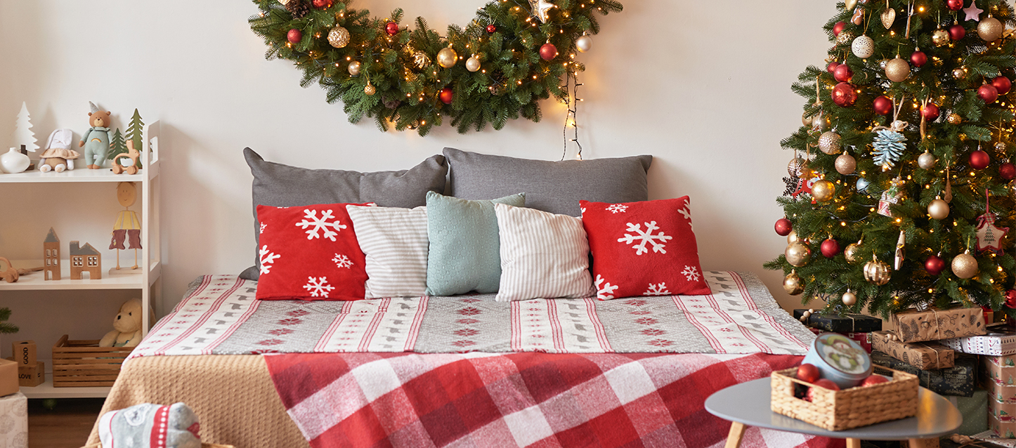 Chambre à coucher décorée de motifs de Noël, coussins, sapin et avec une décoration murale assortie