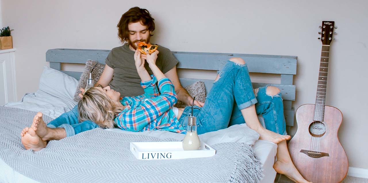pareja comiendo pizza en la cama
