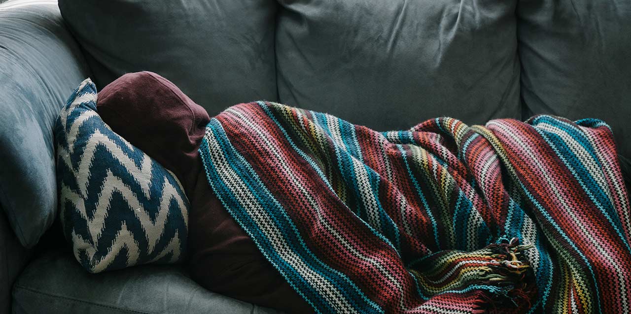 persona durmiendo en el sofá con manta