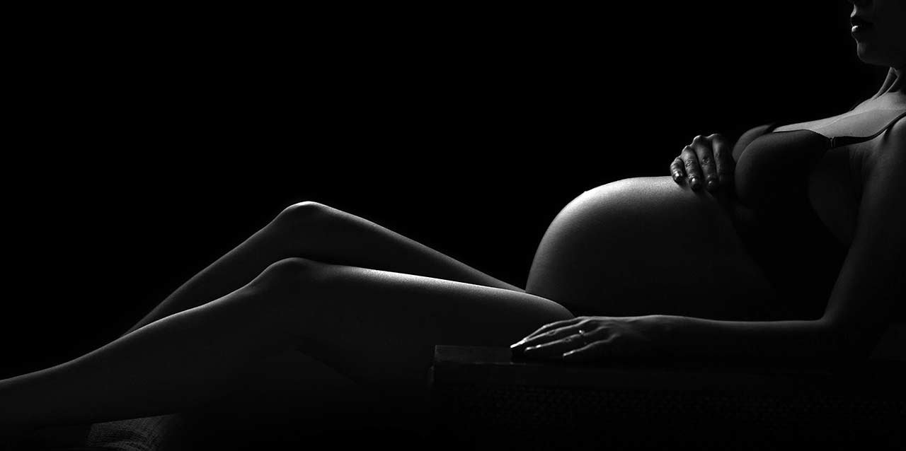 mujer embarazada tumbada en blanco y negro