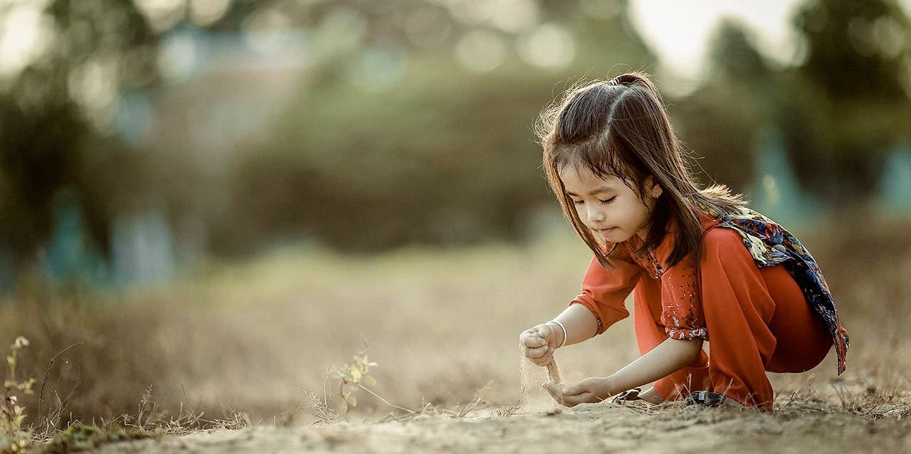 niña jugando con tierra agachada niña jugando con tierra agachada