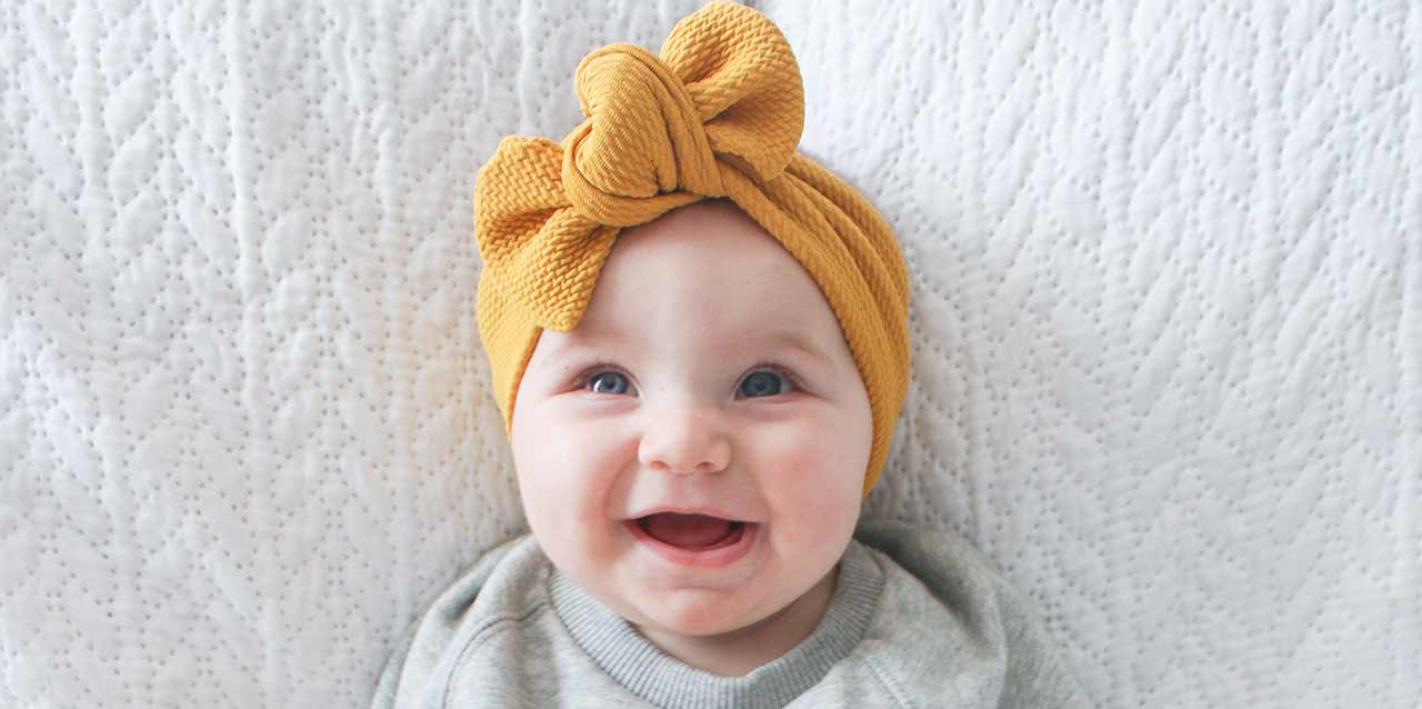 bebé con pañuelo amarillo en cabeza
