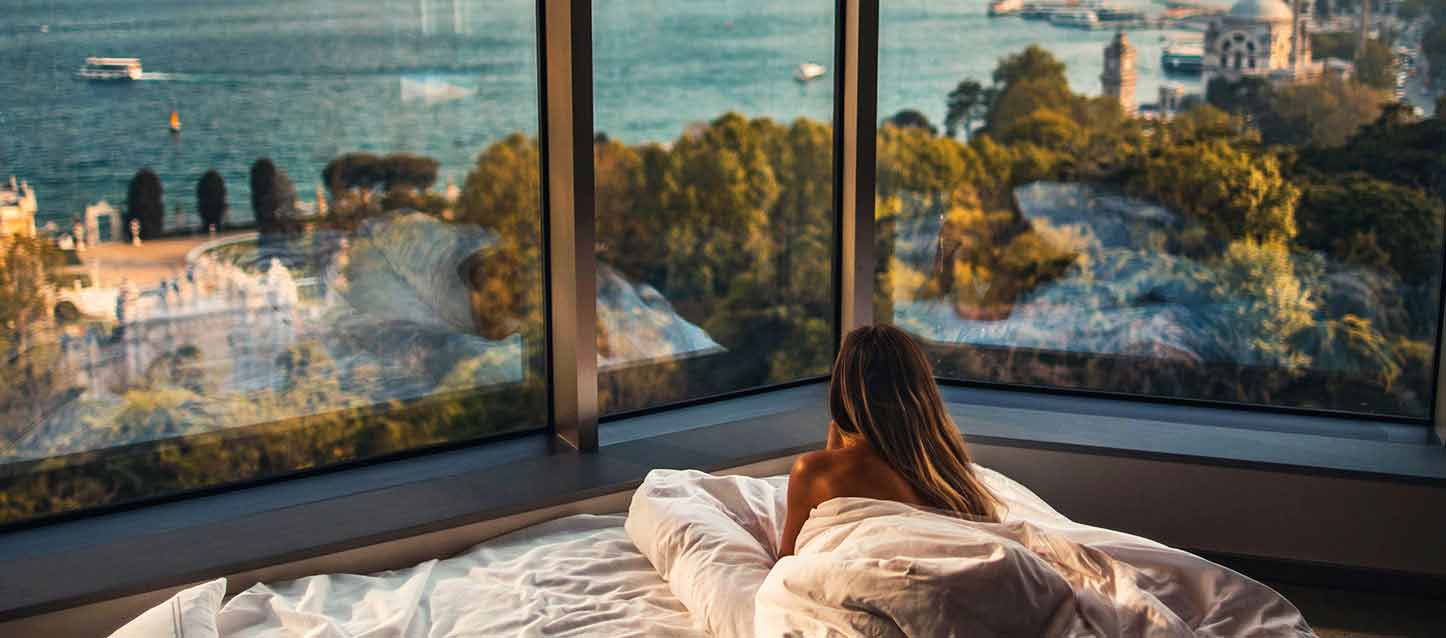 mujer tumbada junto a ventanal con vistas al mar