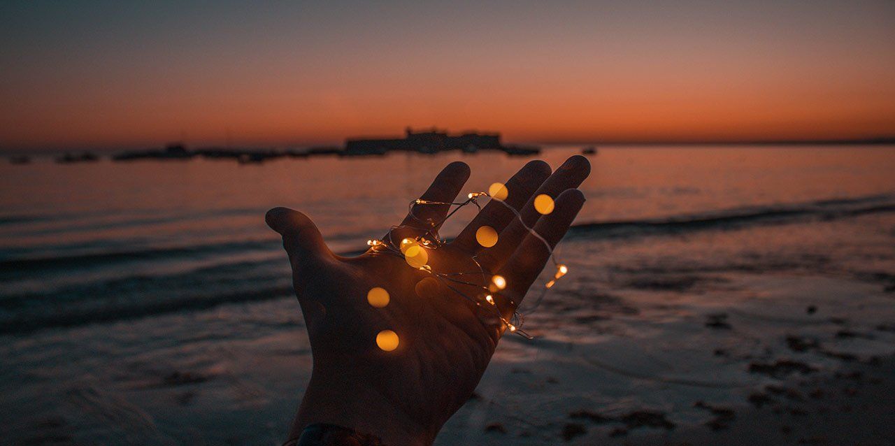 mano con luces led junto al mar