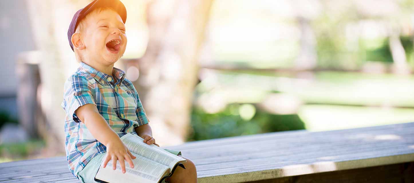 niño riendo sentado con un libro en la mano