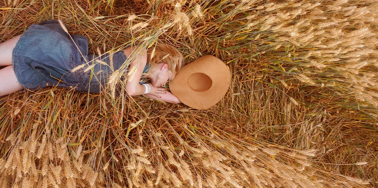 mujer con vestido vaquero tumbada en campo de trigo