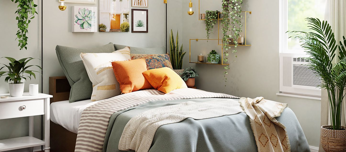dormitorio de adulto decorado con colores relajantes, cama con manta gris, edredon a rayas blancas y marrones, 6 cojines y almohadones y varias estanterias con plantas y objetos decorativos