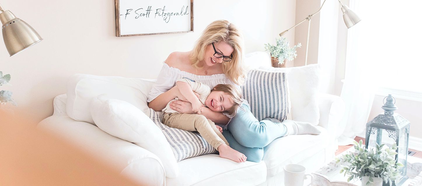 Decoraciones sencillas para habitaciones de niñas madre de pelo rubio y gafas jugando con su hija en el sofa
