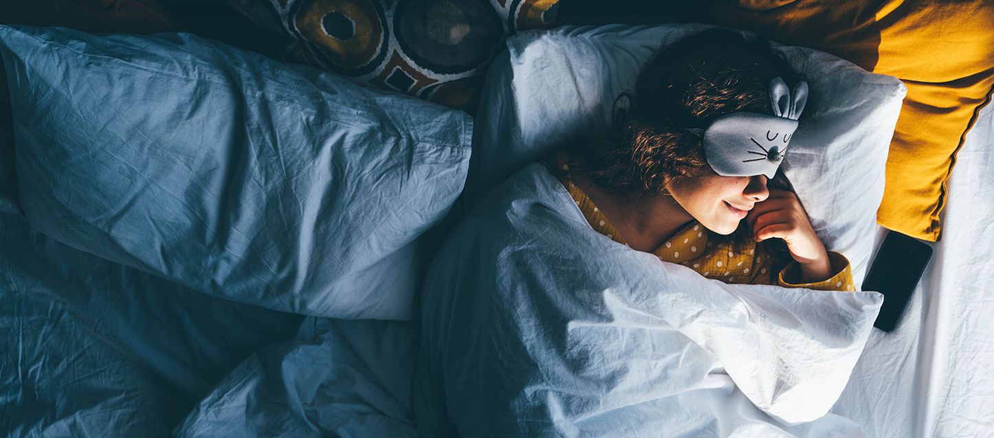 Qué es la higiene postural, una chica durmiendo boca arriba con pijama amarillo con puntos blancos y antifaz