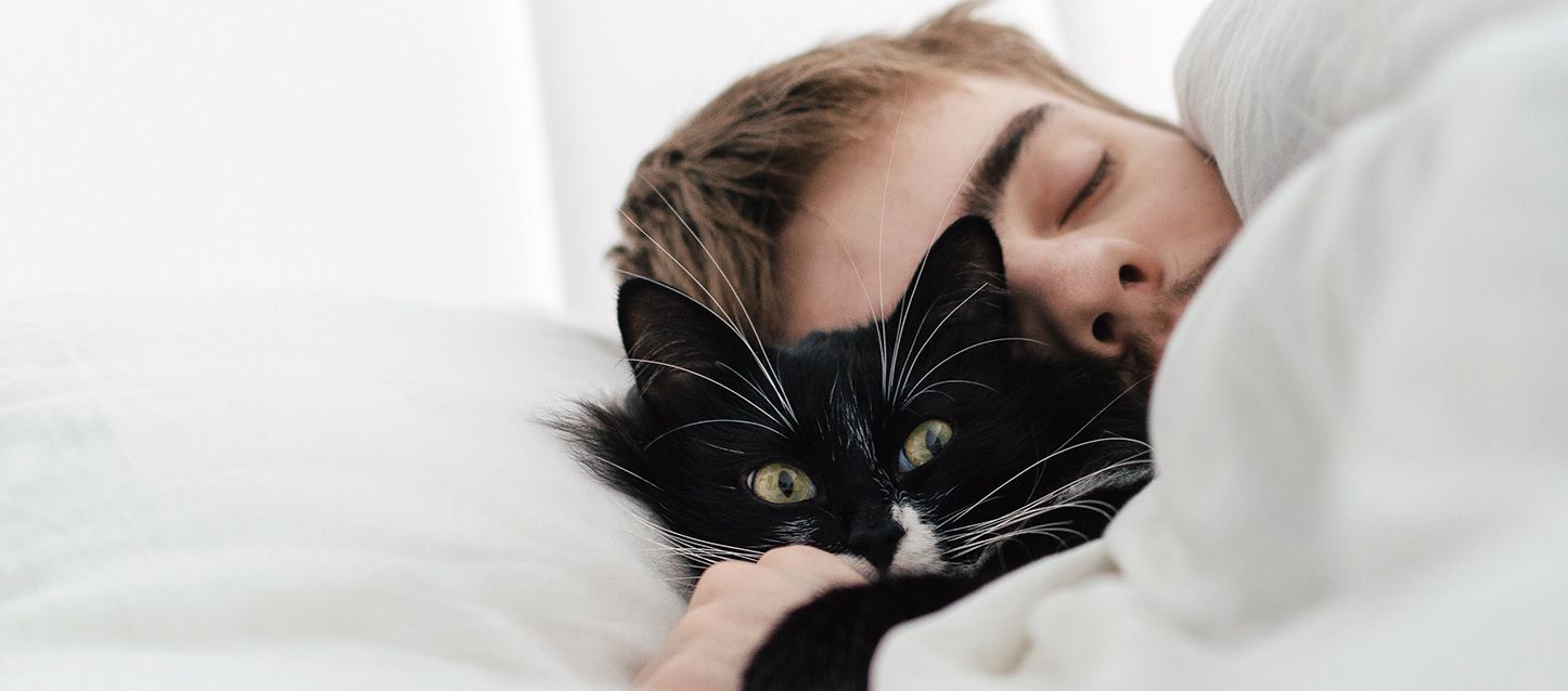 chico durmiendo abrazando a su gato de color negro