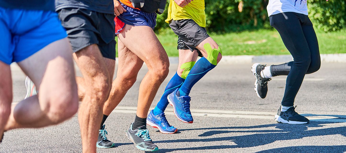 4 personas con ropa deportiva corriendo por una carretera