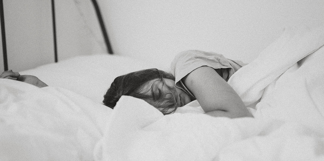 mulher a dormir em cama em preto e branco