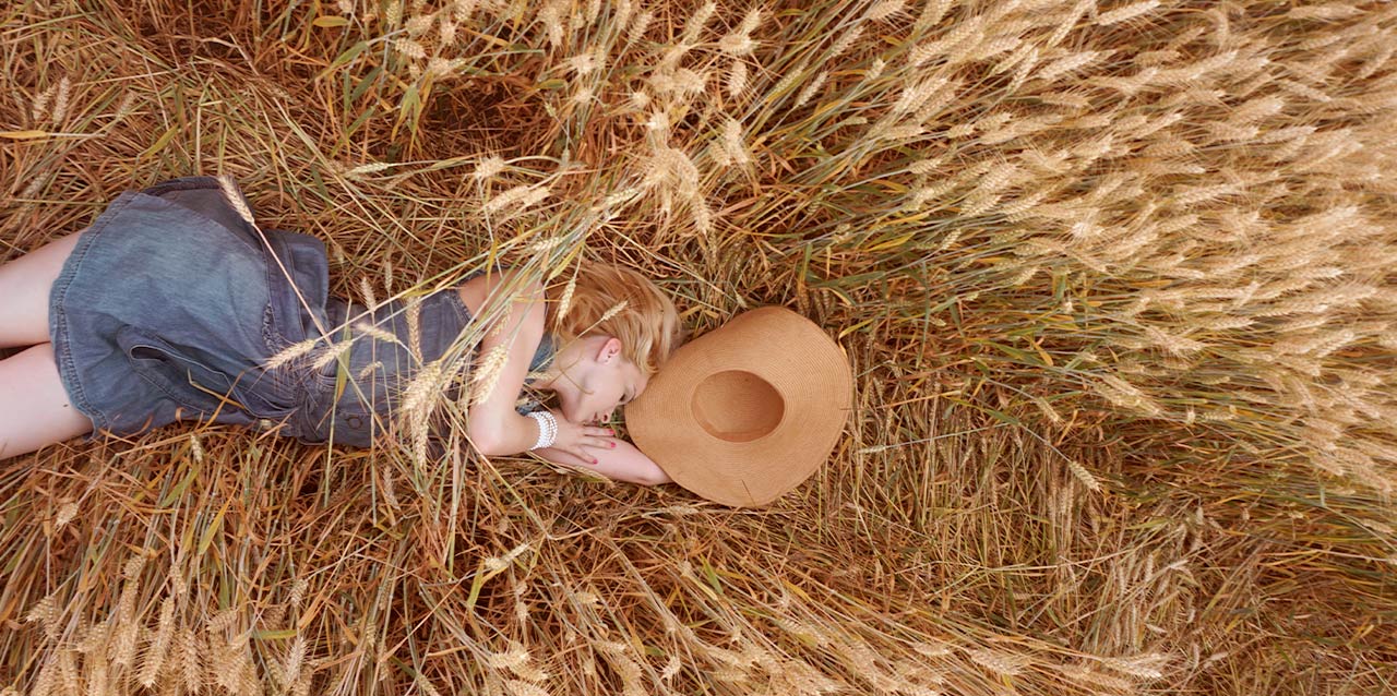rapariga com vestido de ganga a dormir em campo de trigo