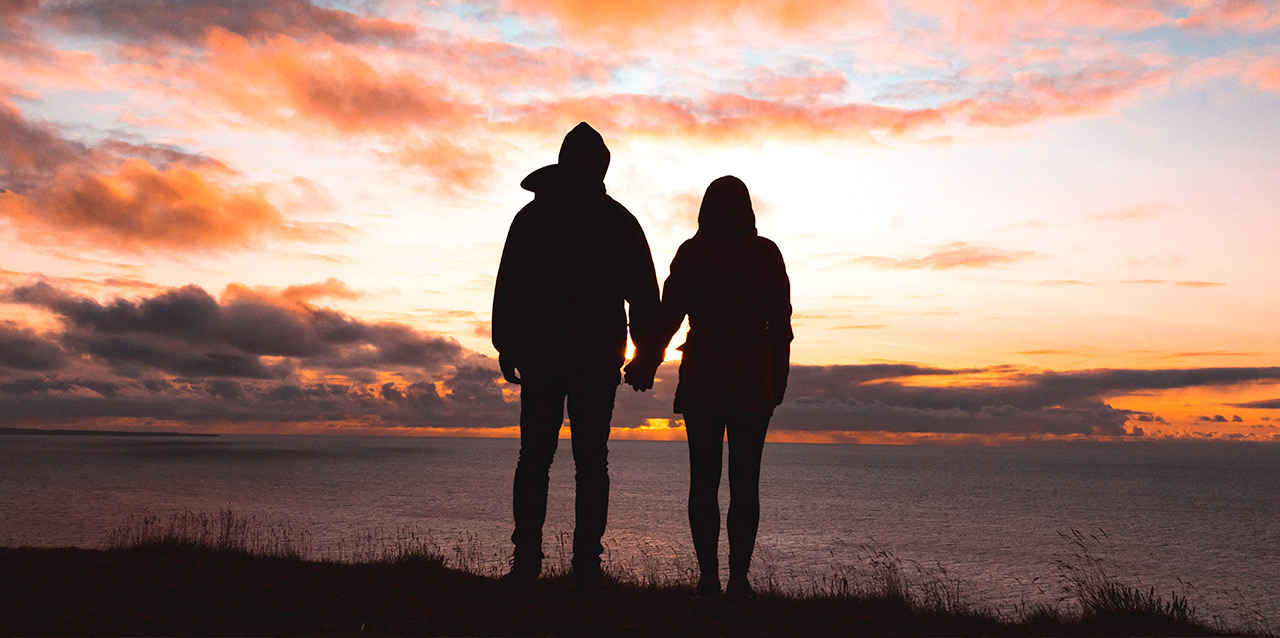casal a contemplar o entardecer junto ao mar