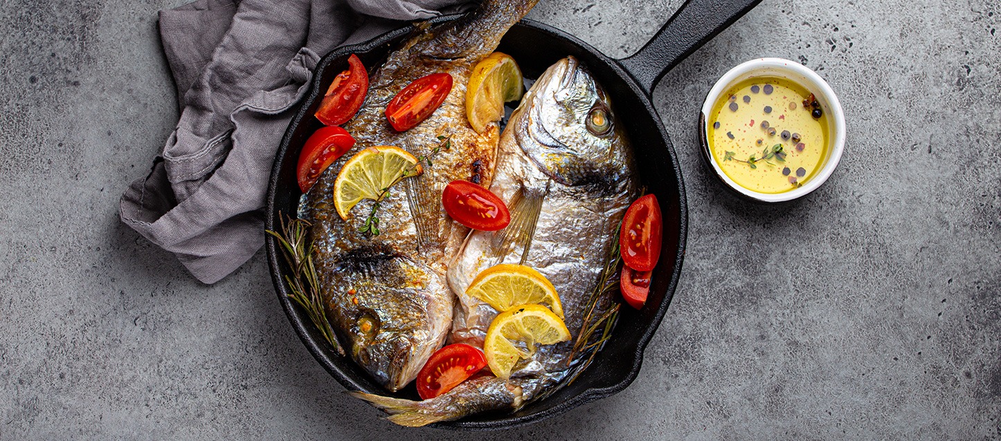 2 peixes cozinhados numa frigideira de ferro fundido