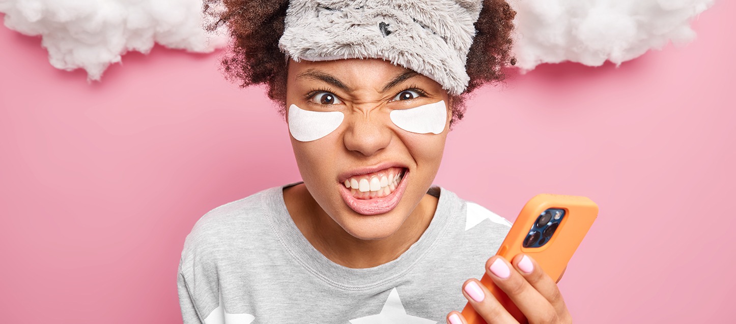 rapariga morena de cabelo afro com máscara dos olhos, com um gesto de malestar e rangendo os dentes